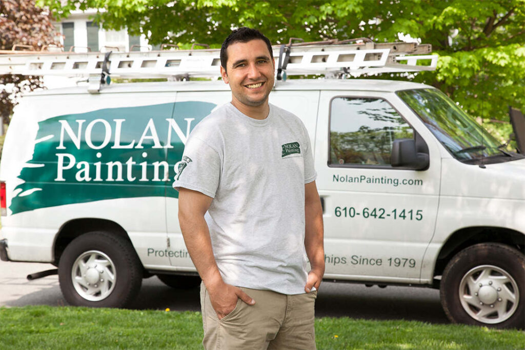 Nolan Painting Company- Havertown, PA Nolan painting employee standing in front of Nolan painting van